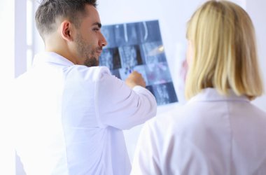 Yakışıklı doktor genç bayan doktorla konuşuyor ve ofisinde otururken notlar alıyor.