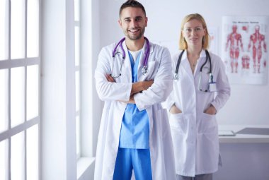 Yakışıklı doktor genç bayan doktorla konuşuyor ve ofisinde otururken notlar alıyor..