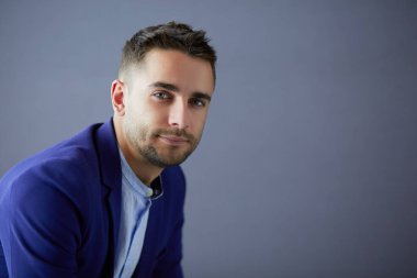 Gri arka planda yalnız oturan genç iş adamı.