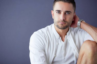 Gri arka planda yalnız oturan genç iş adamı.