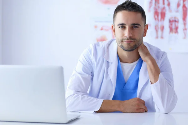 Retrato de un médico varón con portátil sentado en el escritorio en el consultorio médico. — Foto de Stock