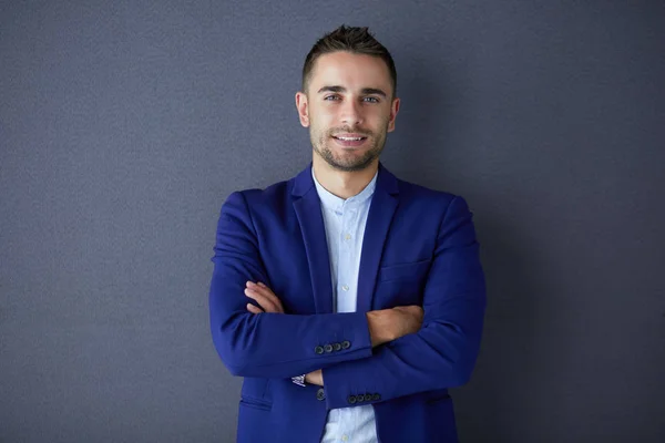 Joven empresario sentado aislado sobre fondo gris. —  Fotos de Stock