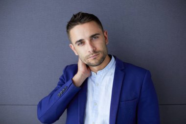 Gri arka planda yalnız oturan genç iş adamı.