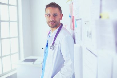 Genç ve kendinden emin erkek doktor portresi tıp ofisinde duruyor..