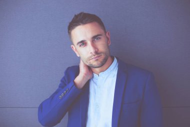 Gri arka planda yalnız oturan genç iş adamı.