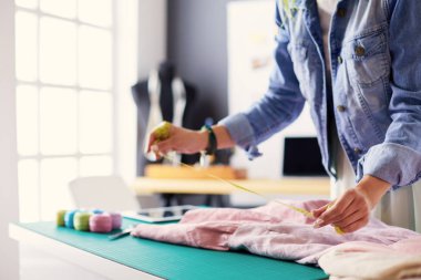 Moda tasarımcısı kadın stüdyoda tasarımları üzerinde çalışıyor.