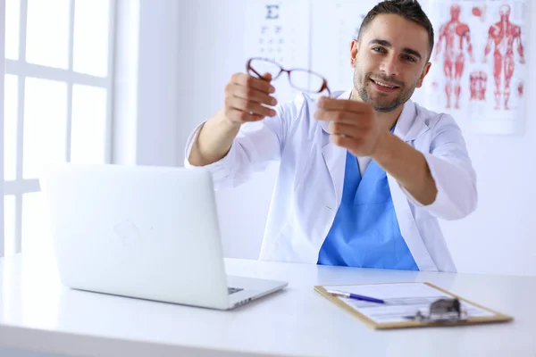 Porträt eines männlichen Arztes mit Laptop am Schreibtisch in der Arztpraxis. — Stockfoto