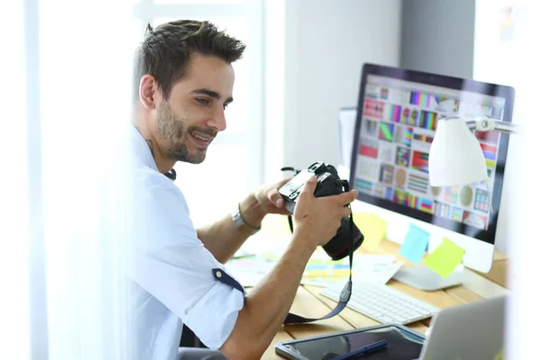 Retrato de jovem designer sentado no estúdio gráfico na frente de laptop e computador enquanto trabalhava online. — Fotografia de Stock