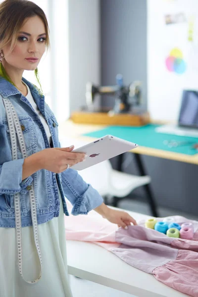 Mulher designer de moda trabalhando com ipad em seus projetos no estúdio — Fotografia de Stock