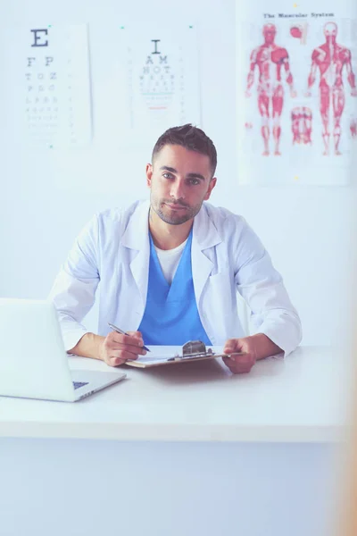 Retrato de un médico varón con portátil sentado en el escritorio en el consultorio médico. — Foto de Stock