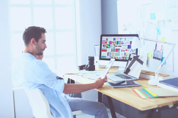 Porträt eines jungen Designers, der im Grafikstudio vor Laptop und Computer sitzt, während er online arbeitet. — Stockfoto