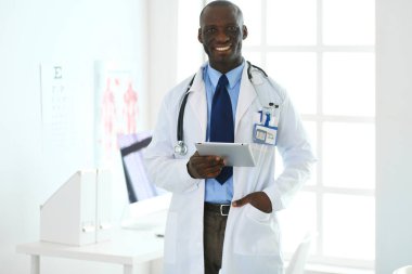 Tablet bilgisayarlı siyahi bir doktor hastanede bekliyor.