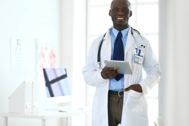 Tablet bilgisayarlı siyahi bir doktor hastanede bekliyor.
