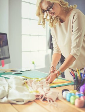 Moda tasarımcısı kadın stüdyoda tasarımları üzerinde çalışıyor.