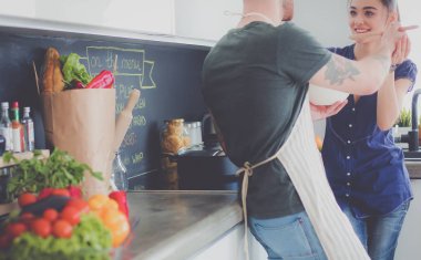 Bir çift evdeki mutfaklarında birlikte yemek pişiriyor.