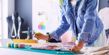 Moda tasarımcısı kadın stüdyoda tasarımları üzerinde çalışıyor.