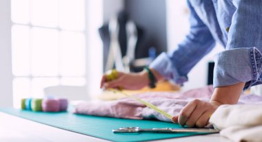 Moda tasarımcısı kadın stüdyoda tasarımları üzerinde çalışıyor.