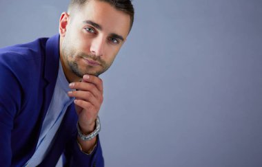 Gri arka planda yalnız oturan genç iş adamı