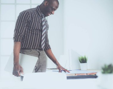 Ofiste bilgisayar ve planlarla çalışan Afrikalı Amerikalı bir mimar.