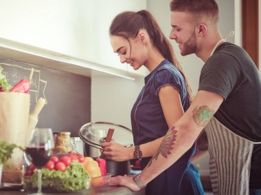 Bir çift evdeki mutfaklarında birlikte yemek pişiriyor.