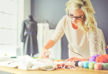 Moda tasarımcısı kadın stüdyoda tasarımları üzerinde çalışıyor.