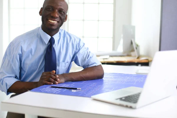 Ofiste bilgisayar ve planlarla çalışan Afrikalı Amerikalı bir mimar. — Stok fotoğraf