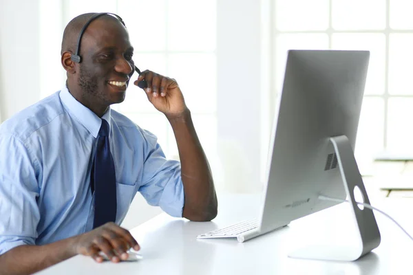 Uomo d'affari afroamericano in cuffia che lavora sul suo portatile — Foto Stock