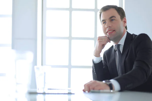 Portrait de jeune homme assis à son bureau dans le bureau. — Photo