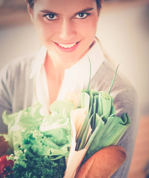 Giovane donna che tiene la borsa della spesa con verdure. In piedi in cucina — Foto Stock