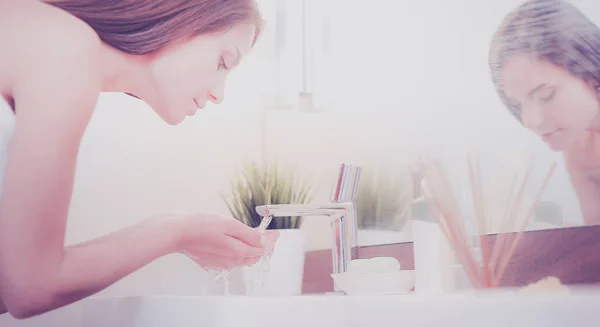 Молодая женщина умывается чистой водой в ванной комнате — стоковое фото