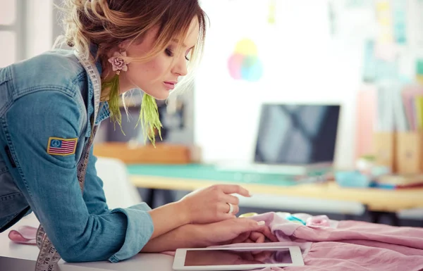 Modedesignerin arbeitet im Atelier mit iPad an ihren Entwürfen — Stockfoto