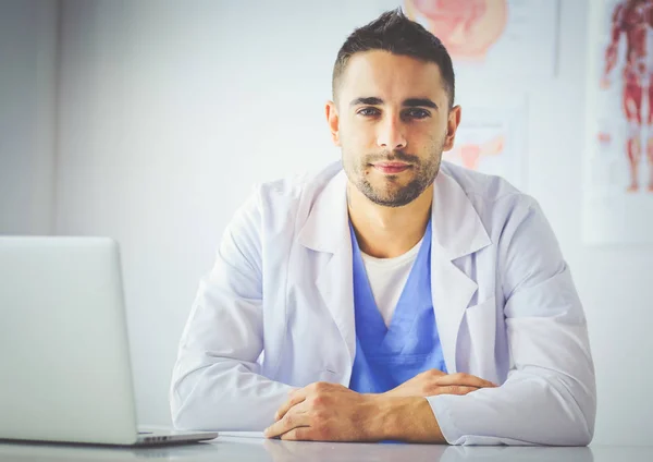 Retrato de un médico varón con portátil sentado en el escritorio en el consultorio médico — Foto de Stock