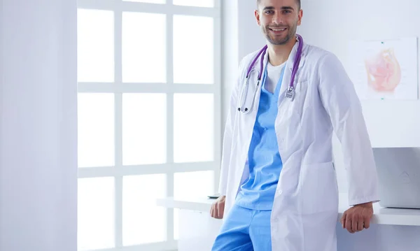 Mladý a sebevědomý mužský lékař portrét stojící v lékařské ordinaci. — Stock fotografie
