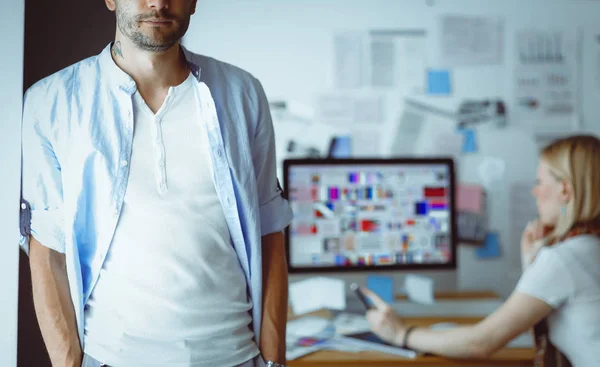 Portrait of young designer in front of laptop and computer while working. Assistant using her mobile at background. — Stock Photo, Image