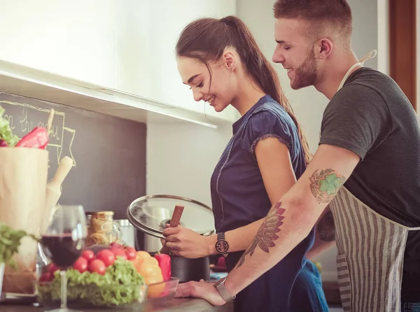 Bir çift evdeki mutfaklarında birlikte yemek pişiriyor.