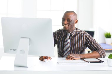 Yakışıklı Afro Amerikalı işadamı Klasik takım elbiseli bir dizüstü bilgisayar kullanarak ve ofiste çalışırken gülümseyen