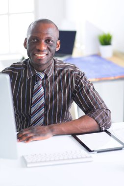 Yakışıklı Afro Amerikalı işadamı Klasik takım elbiseli bir dizüstü bilgisayar kullanarak ve ofiste çalışırken gülümseyen