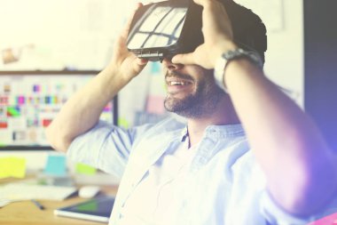 Genç erkek yazılım programcısı ofiste üç boyutlu sanal gerçeklik gözlükleriyle yeni bir uygulama test ediyor..
