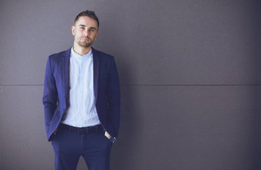 Gri arka planda yalnız oturan genç iş adamı.