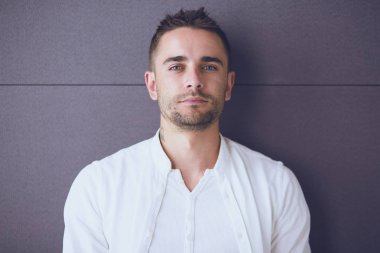 Gri arka planda yalnız oturan genç iş adamı.