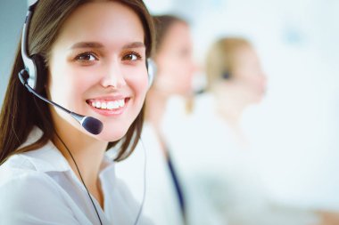 Ofisinde kulaklık ve bilgisayarla gülümseyen iş kadını ya da yardım hattı operatörü