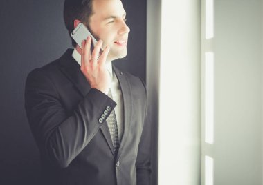 Modern ofiste cep telefonuyla konuşan yakışıklı iş adamı..