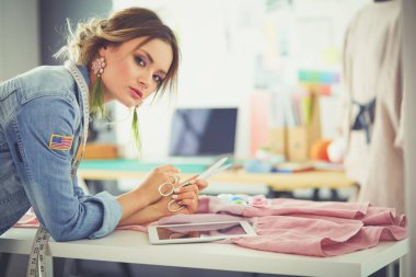 Moda tasarımcısı kadın stüdyoda tasarımları üzerinde çalışıyor.