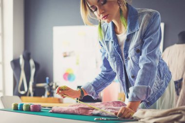 Moda tasarımcısı kadın stüdyoda tasarımları üzerinde çalışıyor.