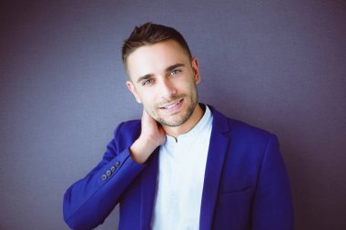 Gri arka planda yalnız oturan genç iş adamı