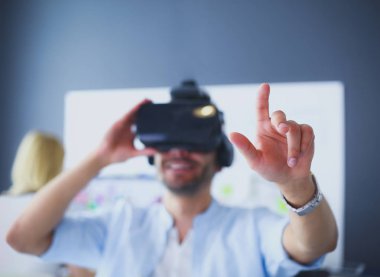 Genç erkek yazılım programcısı ofiste üç boyutlu sanal gerçeklik gözlükleriyle yeni bir uygulama test ediyor..