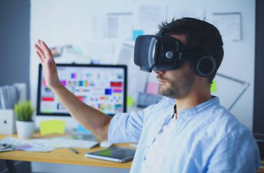 Genç erkek yazılım programcısı ofiste üç boyutlu sanal gerçeklik gözlükleriyle yeni bir uygulama test ediyor..