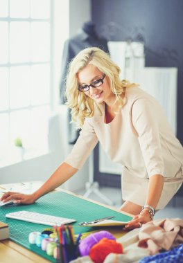 Moda tasarımcısı kadın stüdyoda tasarımları üzerinde çalışıyor.