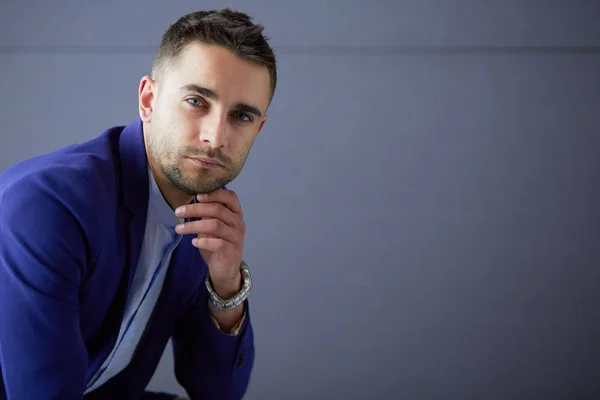 Joven empresario sentado aislado sobre fondo gris. —  Fotos de Stock