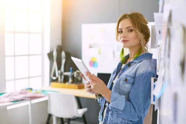 Diseñadora de moda mujer trabajando en sus diseños con ipad en el estudio —  Fotos de Stock